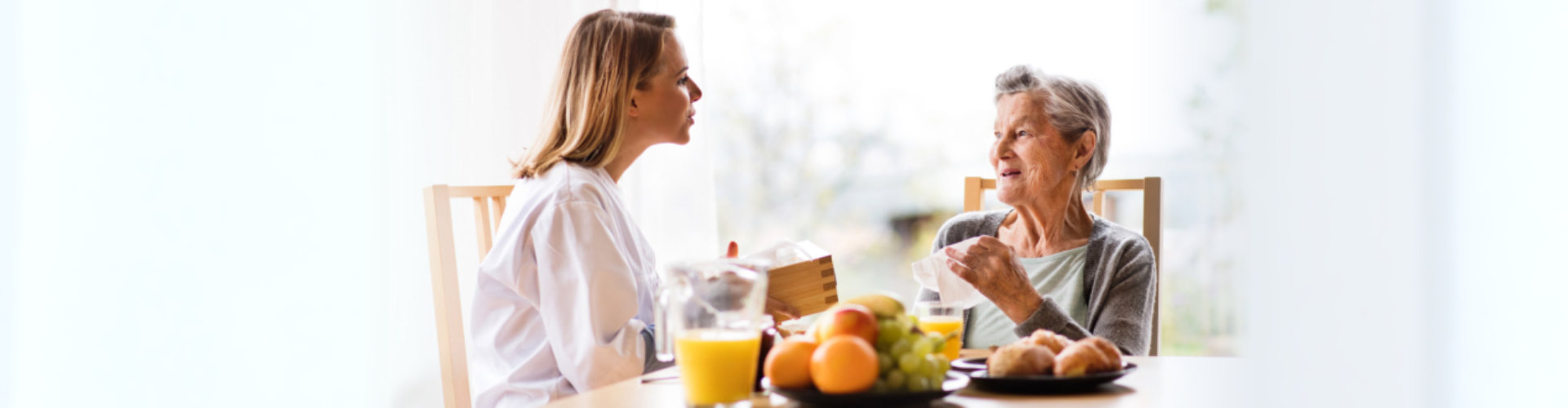 caregiver talking to senior woman with healthy foods in the table